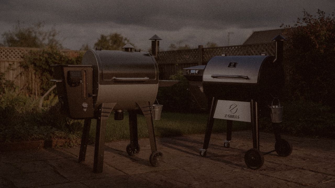Camp Chef Woodwind WiFi 24 and Z Grills 700 Series (ZPG-7002) at night with smoke, wood pellet grills on a dark patio
