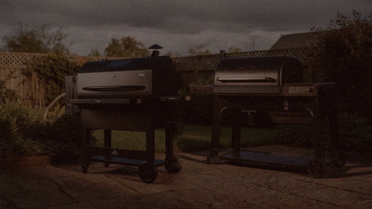 Green Mountain Grills Peak and Traeger Pro 780 at night with smoke, wood pellet grills on a dark patio