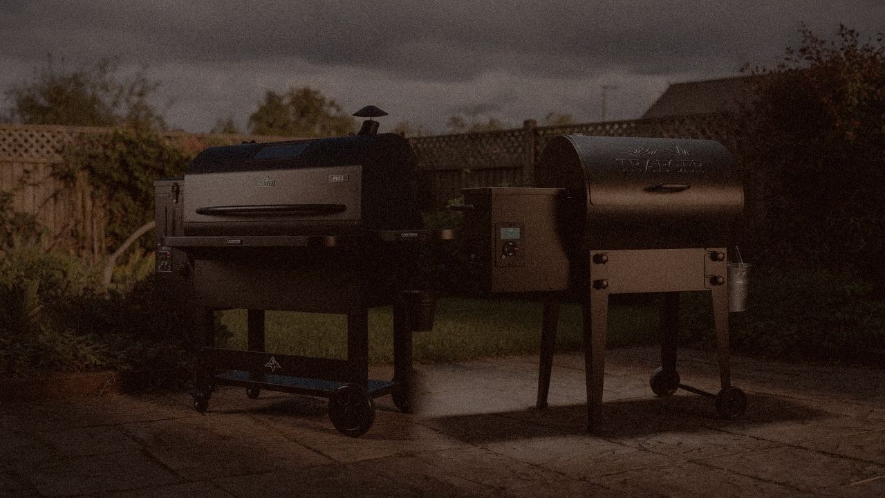 Green Mountain Grills Peak and Traeger Tailgater 20 at night with smoke, wood pellet grills on a dark patio