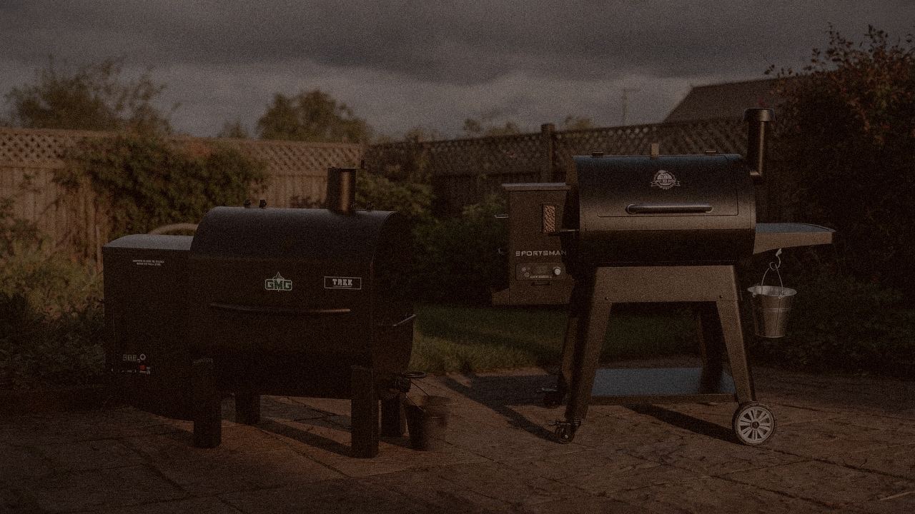 Green Mountain Grills Trek and Pit Boss Sportsman at night with smoke, wood pellet grills on a dark patio