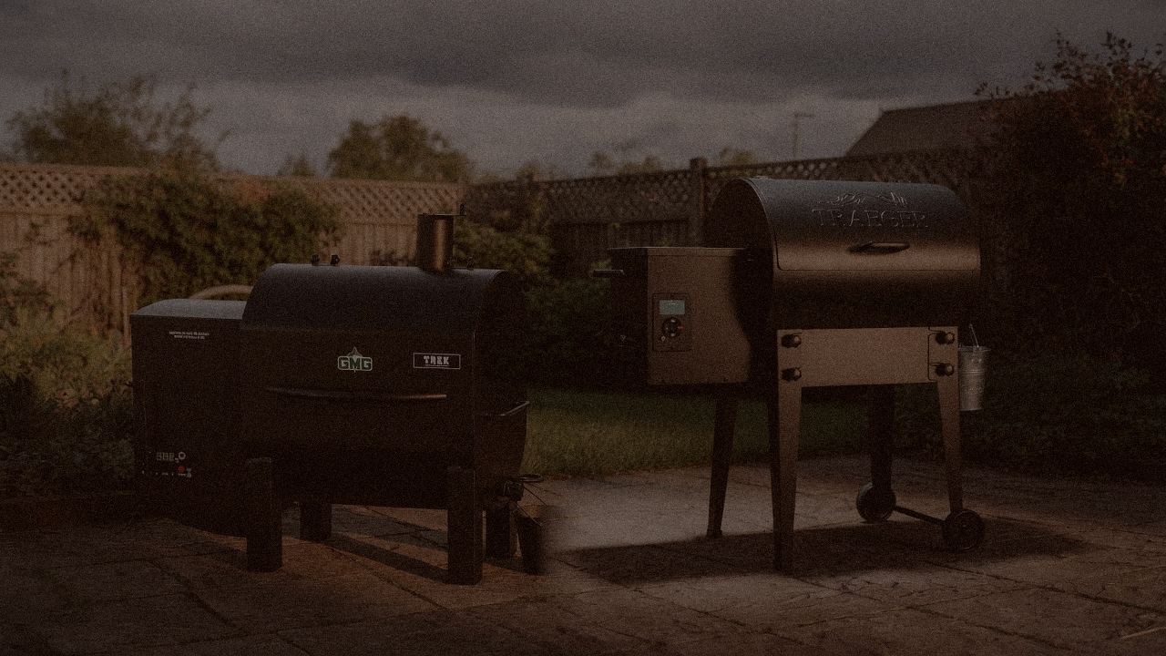 Green Mountain Grills Trek and Traeger Tailgater 20 at night with smoke, wood pellet grills on a dark patio
