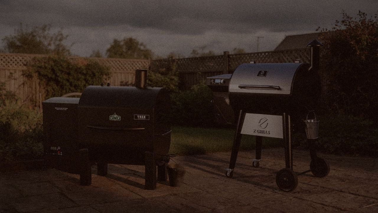 Green Mountain Grills Trek and Z Grills 700 Series (ZPG-7002) at night with smoke, wood pellet grills on a dark patio