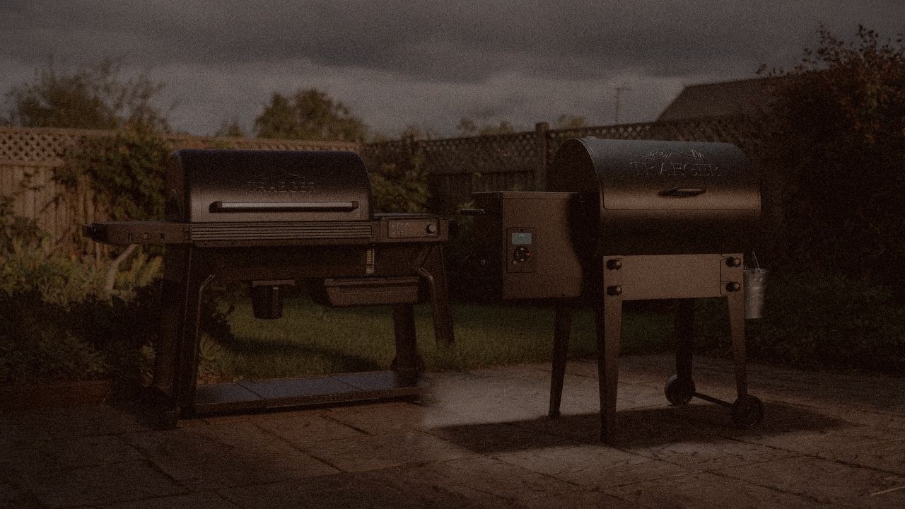 Traeger Pro 780 and Traeger Tailgater 20 at night with smoke, wood pellet grills on a dark patio