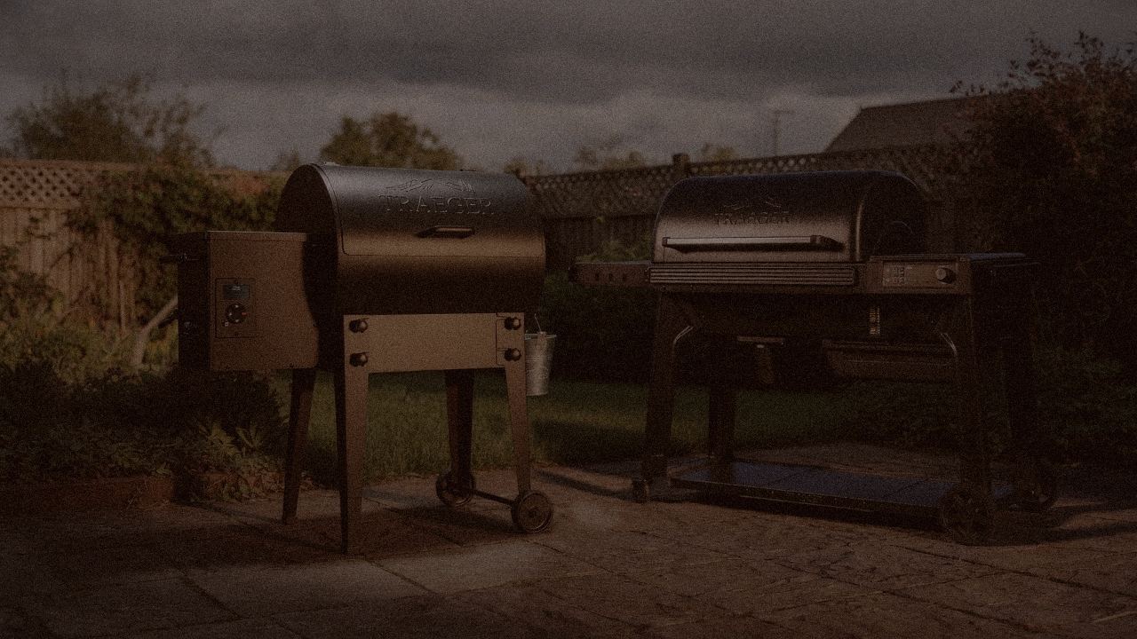 Traeger Tailgater 20 and Traeger Timberline at night with smoke, wood pellet grills on a dark patio