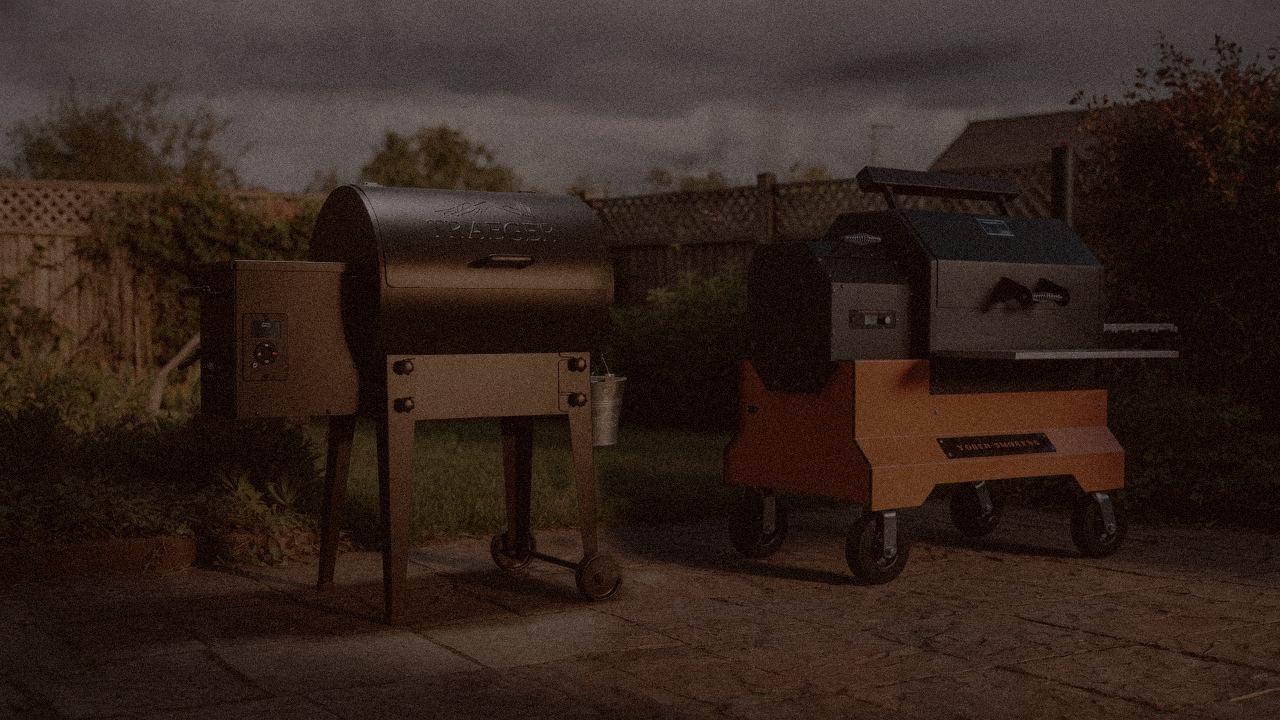 Traeger Tailgater 20 and Yoder Smokers YS640s at night with smoke, wood pellet grills on a dark patio