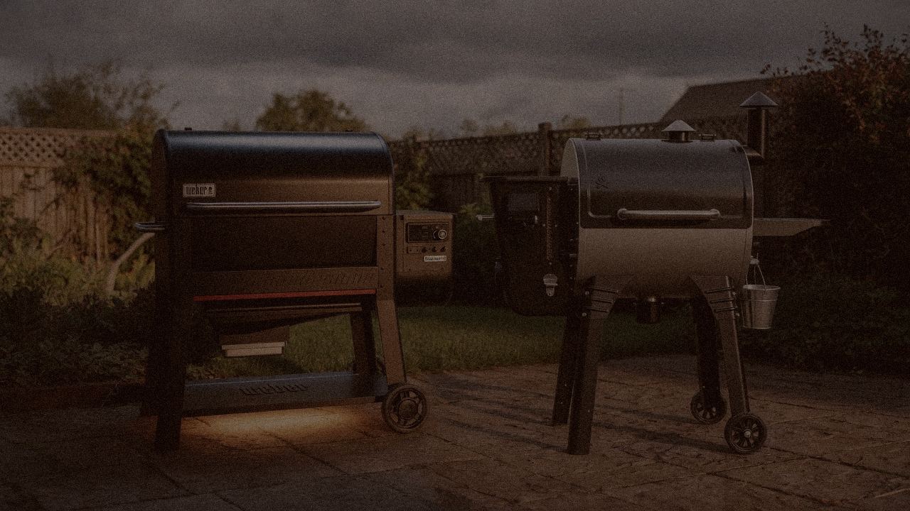 Weber Searwood XL 600 and Camp Chef Woodwind Pro WiFi 24 at night with smoke, wood pellet grills on a dark patio