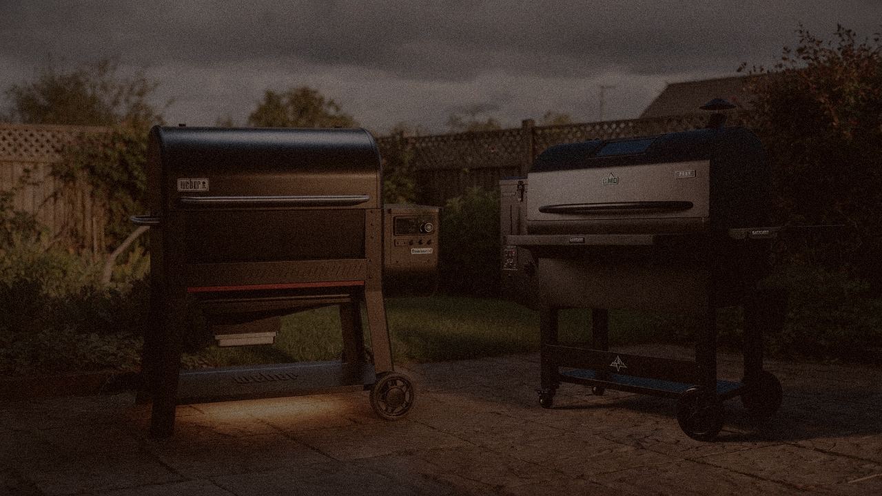 Weber Searwood XL 600 and Green Mountain Grills Peak at night with smoke, wood pellet grills on a dark patio