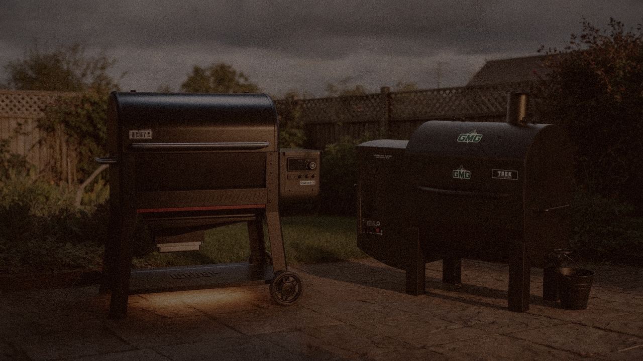 Weber Searwood XL 600 and Green Mountain Grills Trek at night with smoke, wood pellet grills on a dark patio