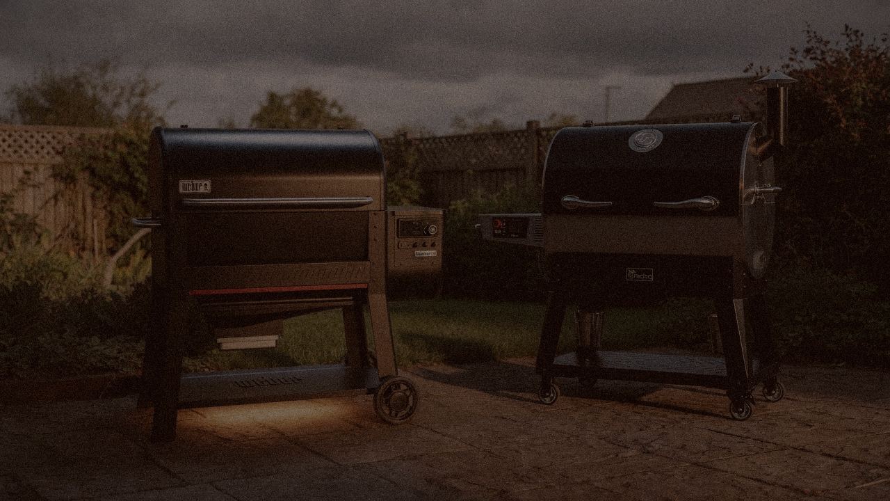 Weber Searwood XL and recteq Flagship 1600 at night with thin blue smoke rising from both, wood pellet grills on a dark patio