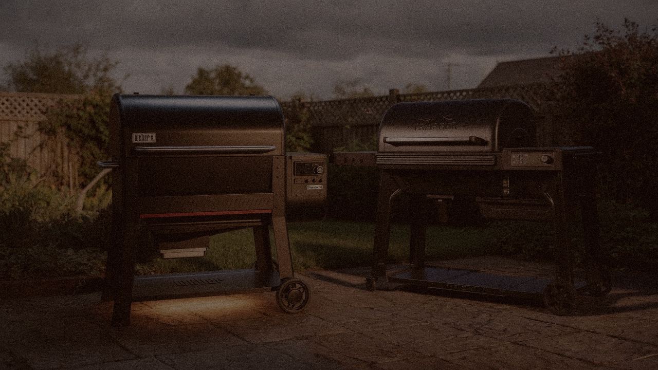 Weber Searwood XL 600 and Traeger Ironwood at night with smoke, wood pellet grills on a dark patio