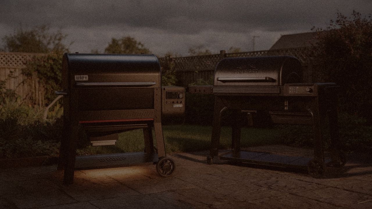 Weber Searwood XL 600 and Traeger Timberline at night with smoke, wood pellet grills on a dark patio
