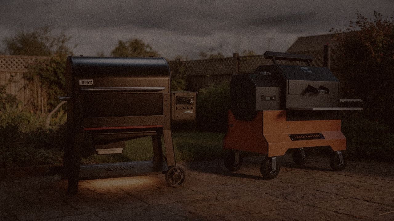 Weber Searwood XL 600 and Yoder Smokers YS640s at night with smoke, wood pellet grills on a dark patio
