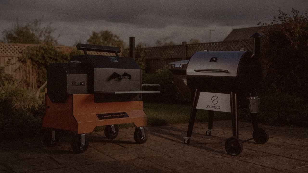 Yoder Smokers YS640s and Z Grills 700 Series (ZPG-7002) at night with smoke, wood pellet grills on a dark patio